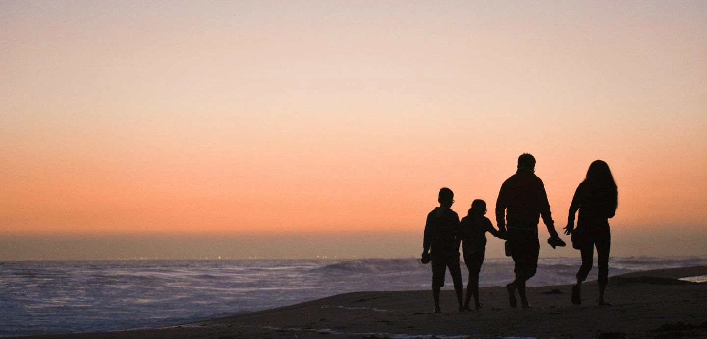 Familia paseando por la playa al atardecer
