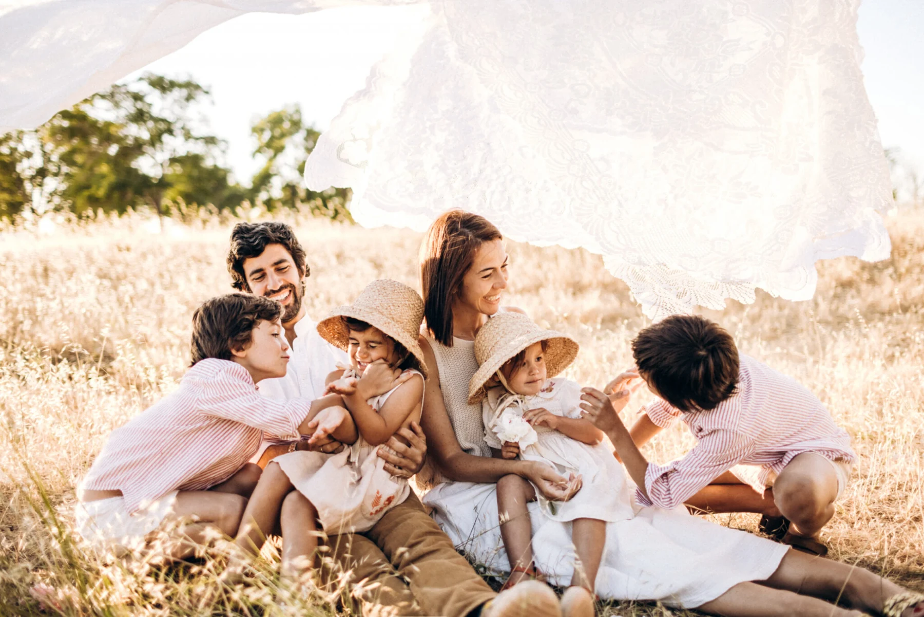 Familia con sus hijos sentada en el campo, sonriendo